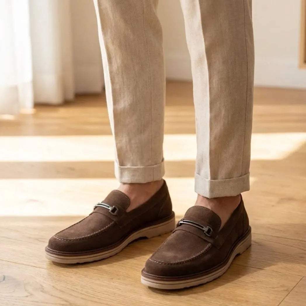 Mocassim Suede Tratorado de Camurça na cor marrom, usado com calça clara de barra dobrada.