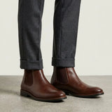 botas Chelsea Milan marrons usadas com calça cinza de barra dobrada.