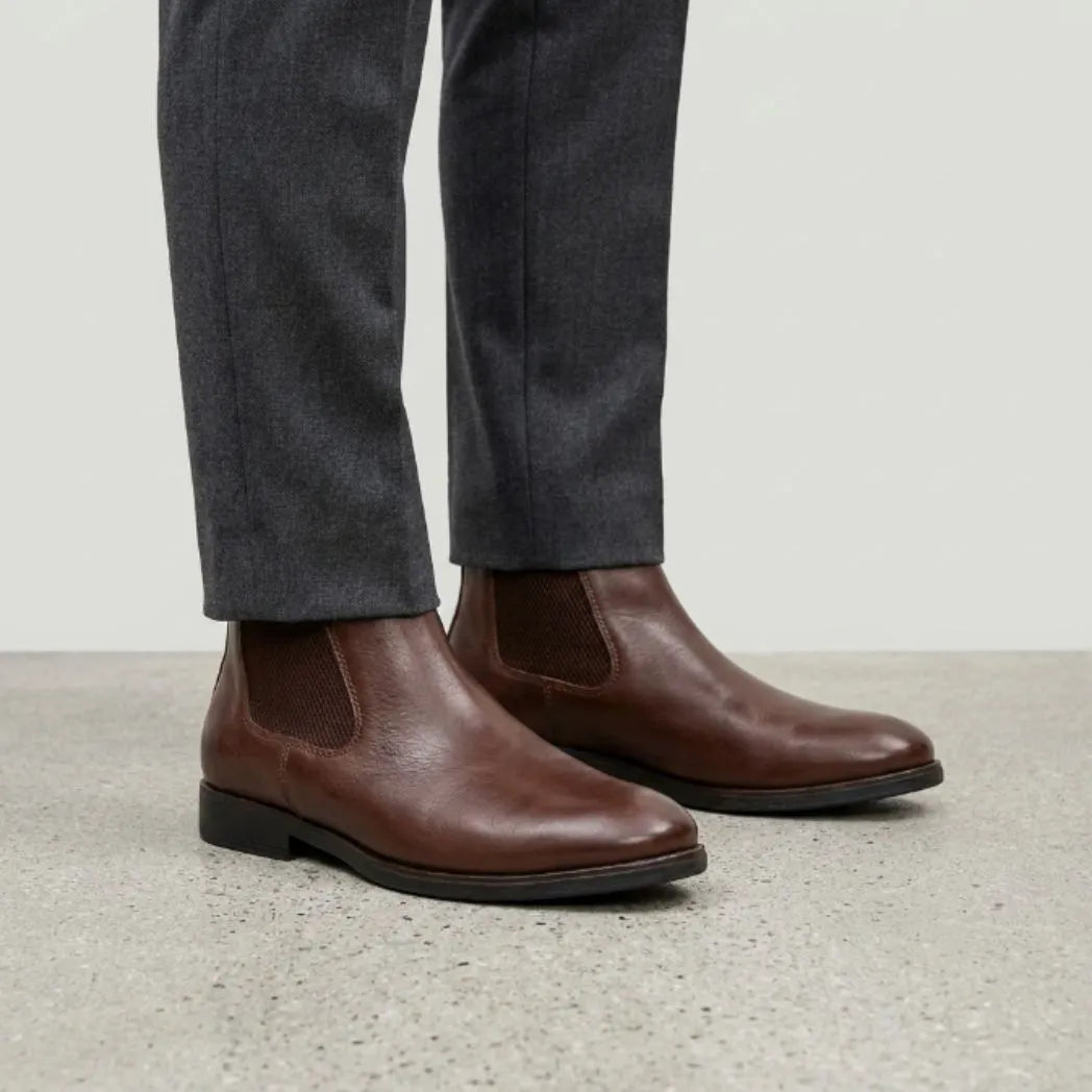 botas Chelsea Londres marrons usadas com calça cinza de barra dobrada.
