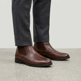 botas Chelsea Londres marrons usadas com calça cinza de barra dobrada.
