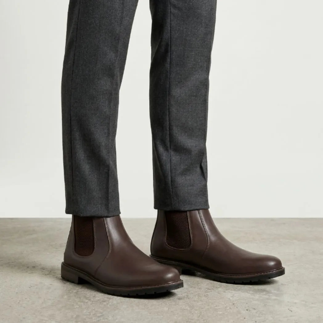 botas Chelsea Sítio marrons usadas com calça cinza de barra dobrada.