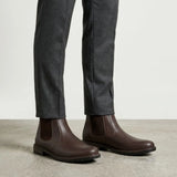 botas Chelsea Sítio marrons usadas com calça cinza de barra dobrada.