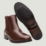 Par de botas Chelsea Londres marrons, com um dos solados voltado para a câmera.