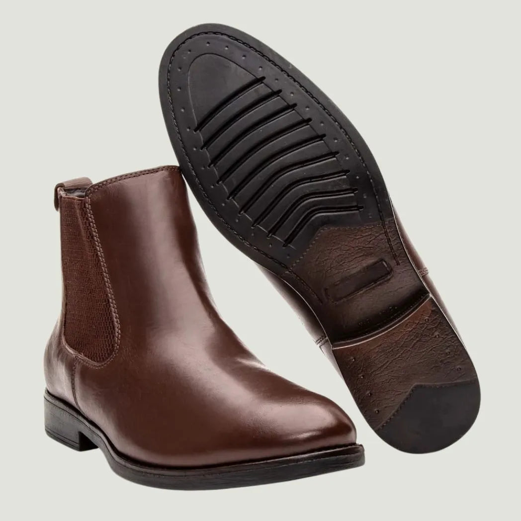 Par de botas Chelsea Londres marrons, com um dos solados voltado para a câmera.