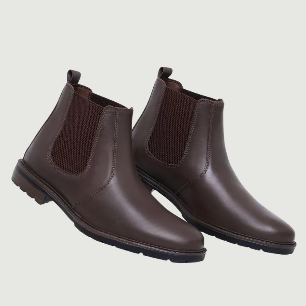 Par de botas Chelsea Sítio marrons em perspectiva, com elásticos laterais visíveis.
