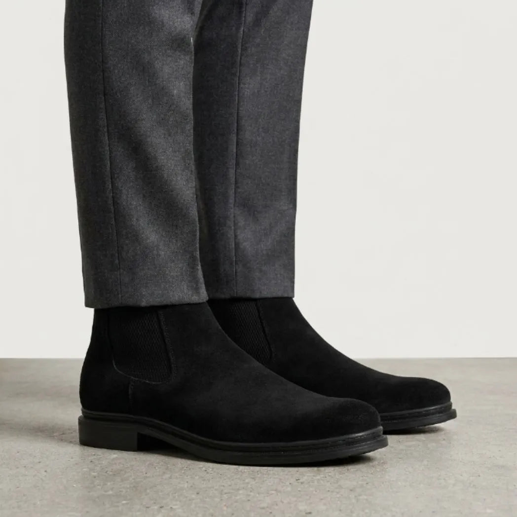botas Chelsea de Camurça pretas usadas com calça cinza de barra dobrada.