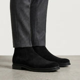 botas Chelsea de Camurça pretas usadas com calça cinza de barra dobrada.
