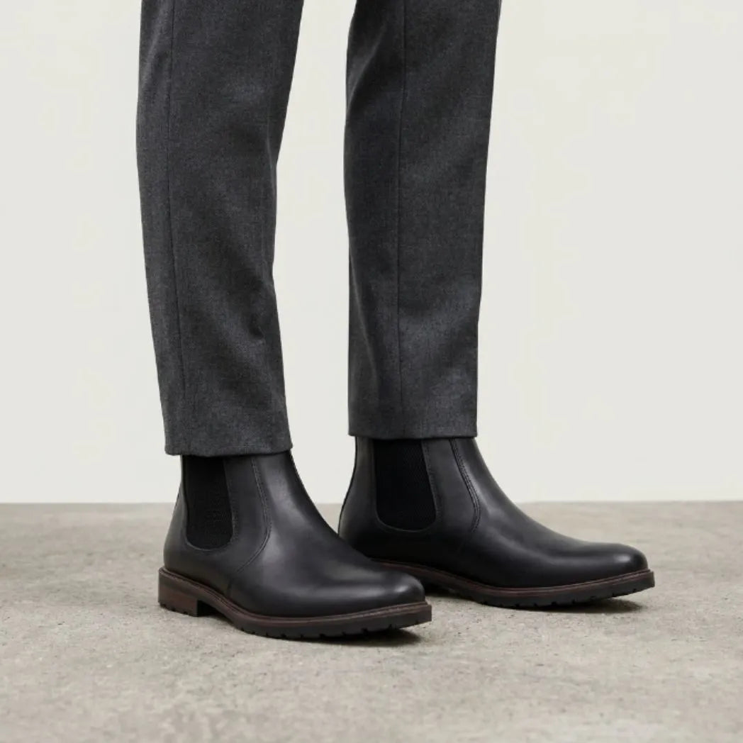 botas Chelsea Sítio pretas usadas com calça cinza de barra dobrada.