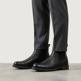 botas Chelsea Vitiello pretas usadas com calça cinza de barra dobrada.