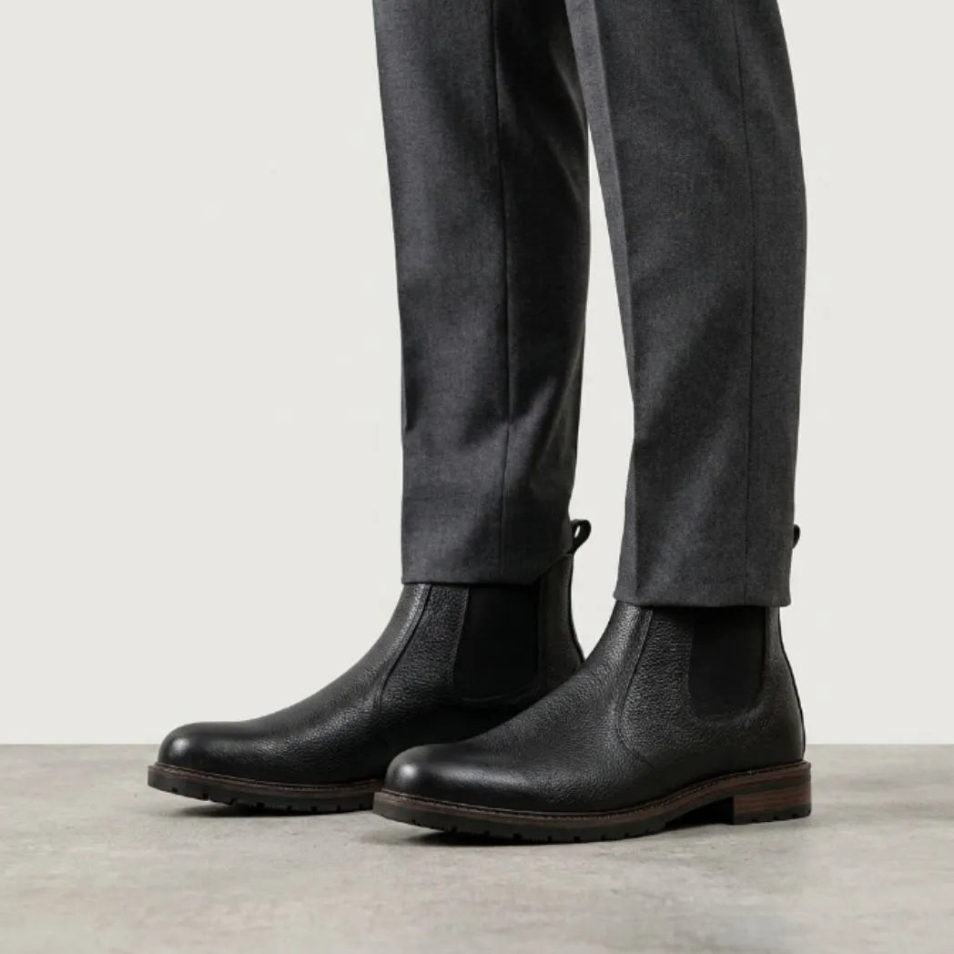 botas Chelsea Vitiello pretas usadas com calça cinza de barra dobrada.