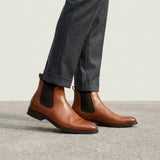 botas Chelsea Clássicas marrons usadas com calça cinza de barra dobrada.
