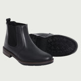 Par de botas Chelsea Sítio pretas, com um dos solados voltado para a câmera.