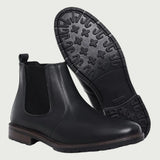 Par de botas Chelsea Sítio pretas, com um dos solados voltado para a câmera.