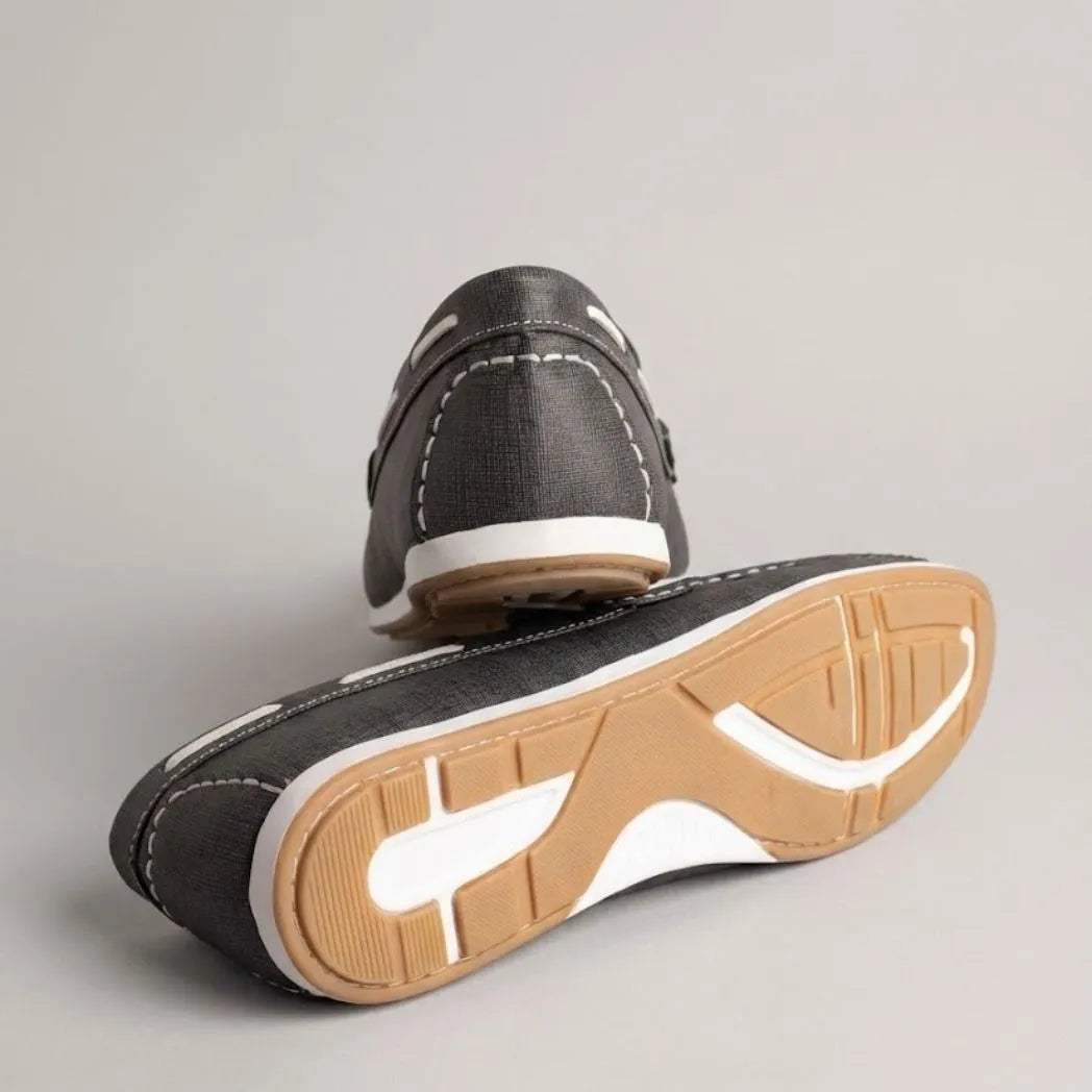 Par do modelo Mocassim Casual Canvas em Lona, na cor cinza-escuro, com um dos solados voltado para a câmera.