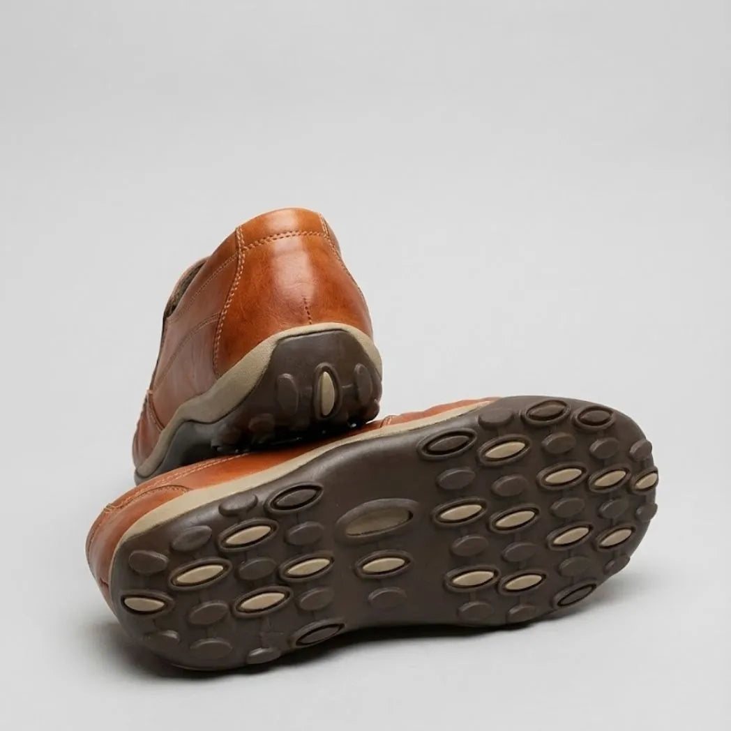 Mocassim Casual Comfort Daytona Drive: par marrom com um sapato virado, mostrando a sola escura com detalhes ovais claros.