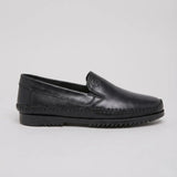 Mocassim Casual Dakota Rust: modelo preto de perfil, com emblema em relevo e sola preta.