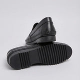 Mocassim Casual Dakota Rust: par preto com um sapato virado, mostrando a sola preta com sulcos.