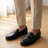 Mocassim Casual Loafer Nero na cor preto, usado com calça clara de barra dobrada.