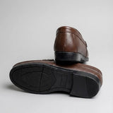 Par do modelo Mocassim Casual Loafer Nero, na cor marrom, com um dos solados voltado para a câmera.