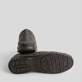Par do modelo Mocassim Cognac de Couro, na cor cinza-escuro, com um dos solados voltado para a câmera.