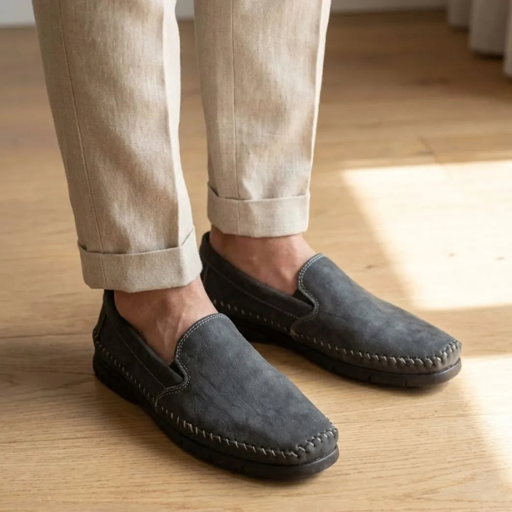 Mocassim Cognac de Couro na cor cinza-escuro, usado com calça clara de barra dobrada.