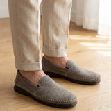 Mocassim Cognac de Couro na cor cinza, usado com calça clara de barra dobrada.