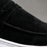 Mocassim Derby de Camurça: detalhe da textura preta, da faixa frontal e da costura.