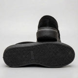 Mocassim Derby de Camurça: par preto com um sapato virado, mostrando a sola preta com relevo em zigue-zague.