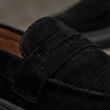 Mocassim Derby de Camurça: detalhe da textura preta, da faixa frontal e da costura.