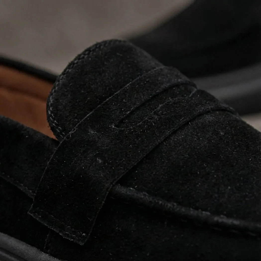 Mocassim Derby de Camurça: detalhe da textura preta, da faixa frontal e da costura.