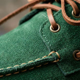 Mocassim Dockside de Camurça: detalhe da textura verde, dos ilhós dourados e da costura clara.
