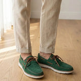 Mocassim Dockside de Camurça: par verde com cadarços marrons usado com calça clara dobrada na barra.