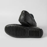 Par do modelo Mocassim Driver Cruise de Couro Preto, na cor preto, com um dos solados voltado para a câmera.