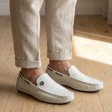 Mocassim Driver Cruise de Couro na cor branco, usado com calça clara de barra dobrada.
