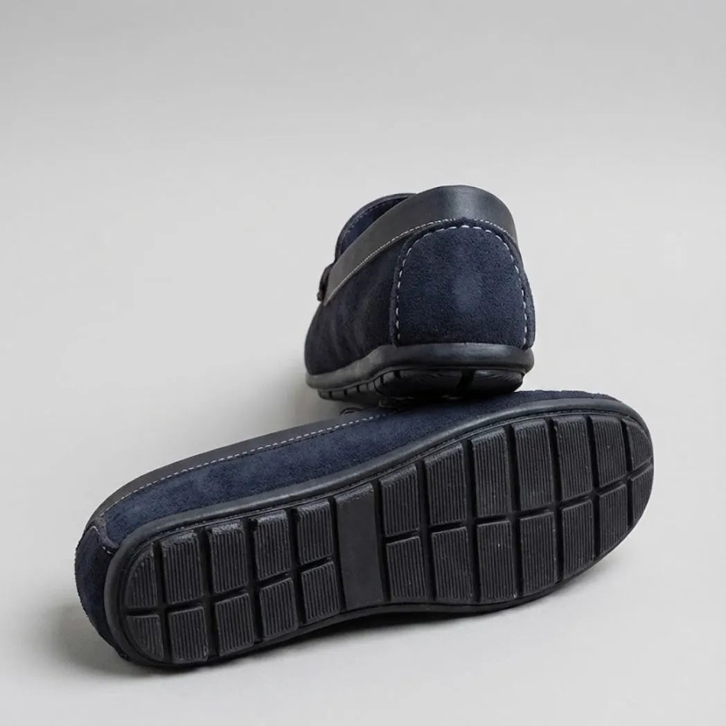 Par do modelo Mocassim Driver Dune de Camurça, na cor preto, com um dos solados voltado para a câmera.