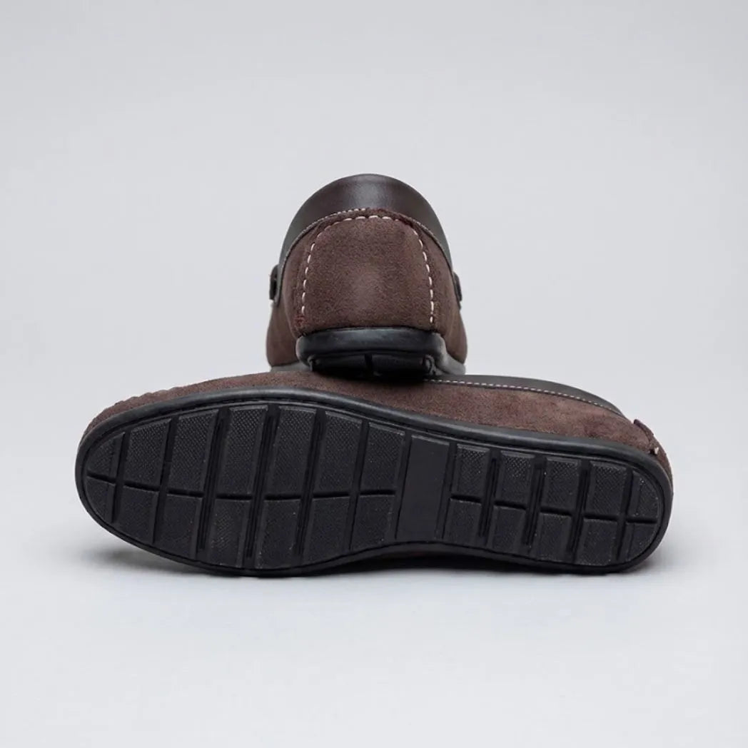 Par do modelo Mocassim Driver Dune de Camurça, na cor marrom, com um dos solados voltado para a câmera.