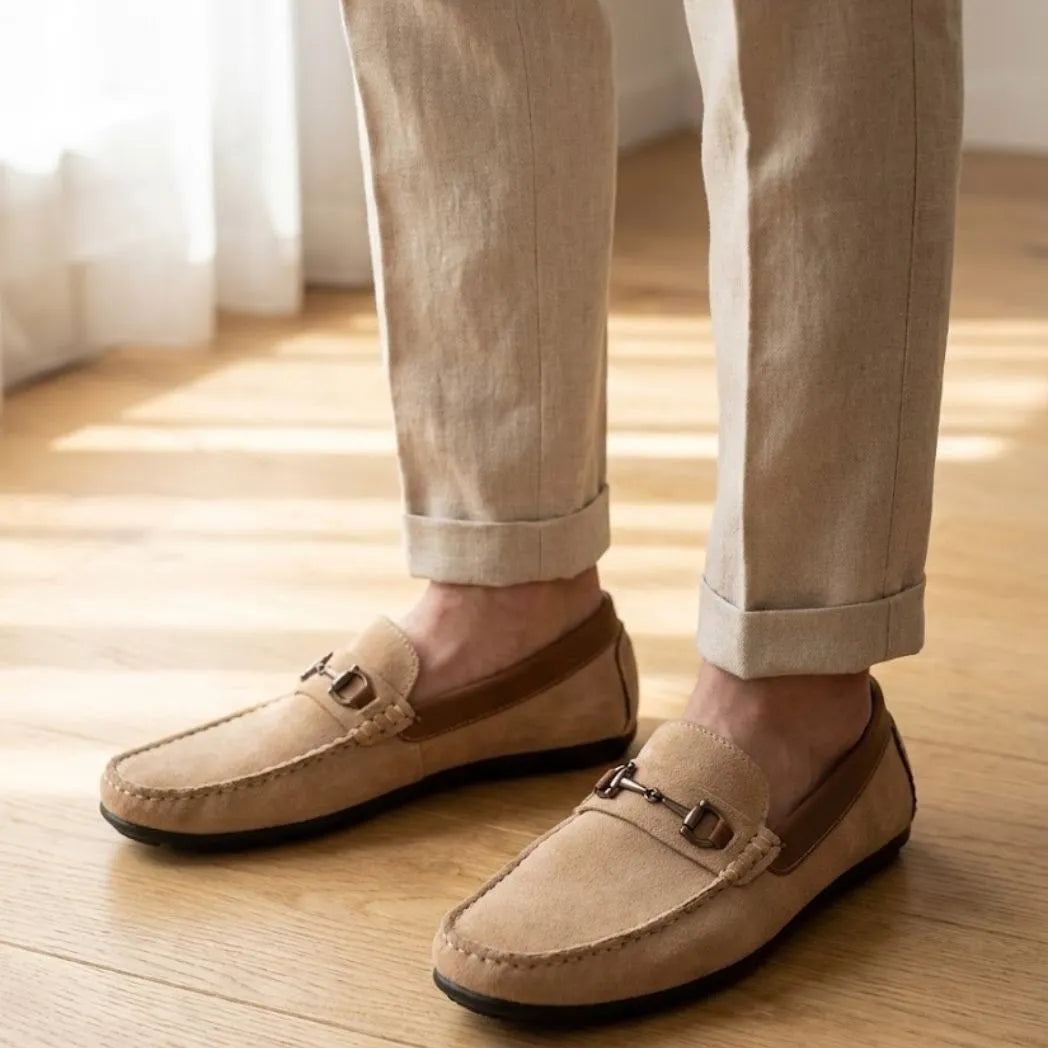 Mocassim Driver Dune de Camurça na cor bege, usado com calça clara de barra dobrada.