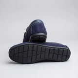 Par do modelo Mocassim Driver Dune de Camurça, na cor azul-escuro, com um dos solados voltado para a câmera.