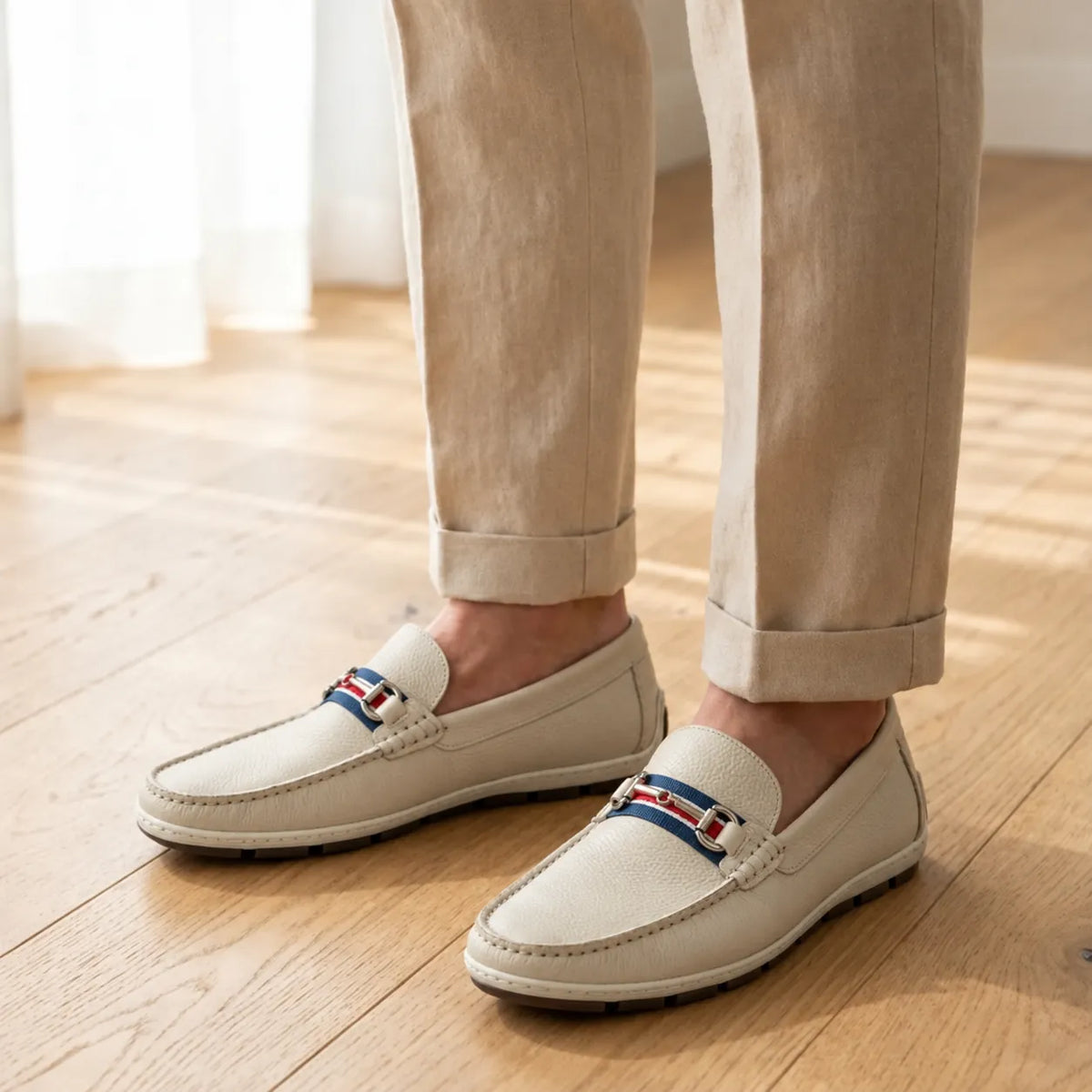 Mocassim Driver Heritage de Couro Branco nos pés, com faixa azul, branca e vermelha, ferragem prateada e solado driver.