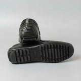 Par do modelo Mocassim Driver Penny de Couro, na cor preto, com um dos solados voltado para a câmera.