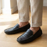 Mocassim Driver Penny de Couro na cor preto, usado com calça clara de barra dobrada.