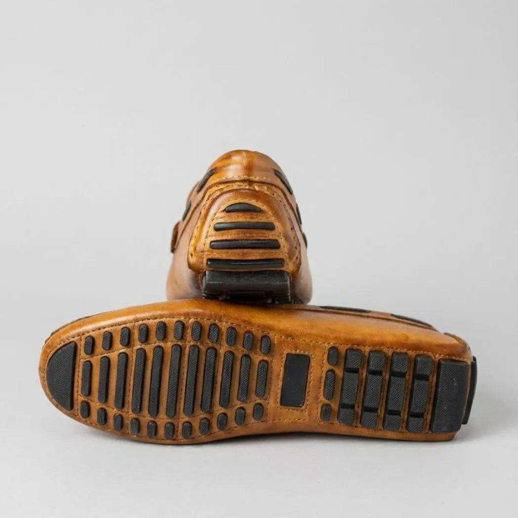Par do modelo Mocassim Driver Penny de Couro, na cor laranja, com um dos solados voltado para a câmera.