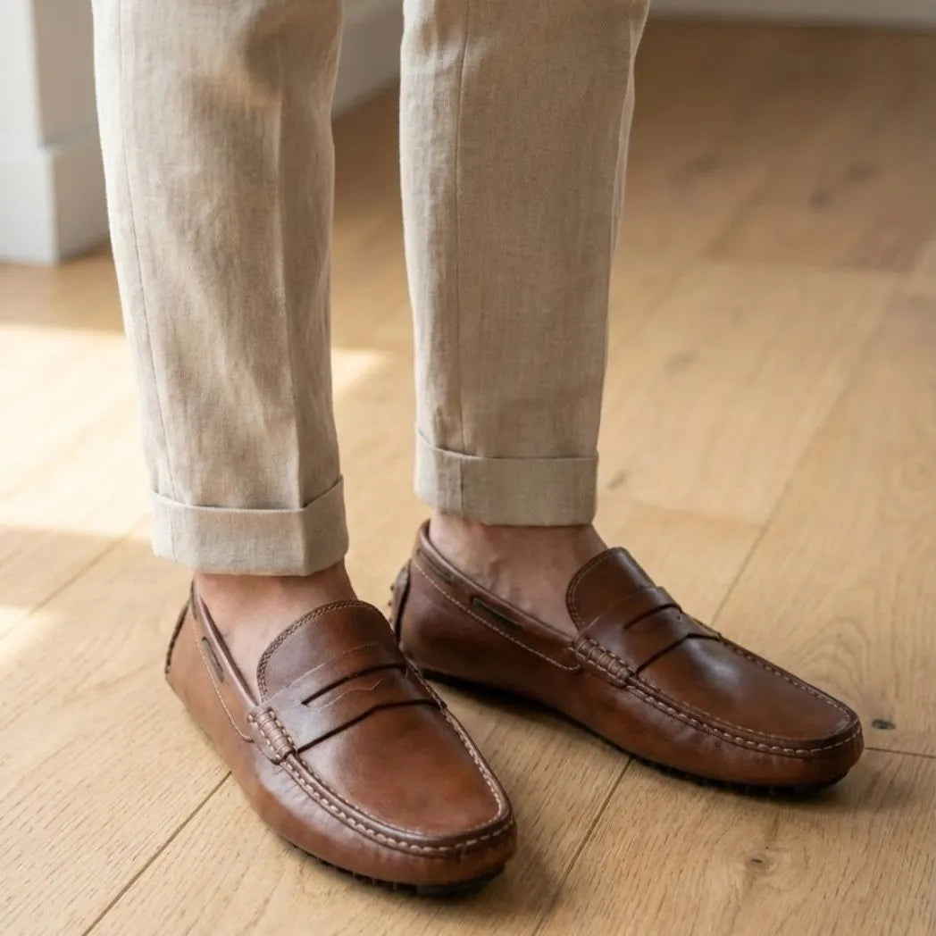 Mocassim Driver Penny de Couro na cor marrom, usado com calça clara de barra dobrada.