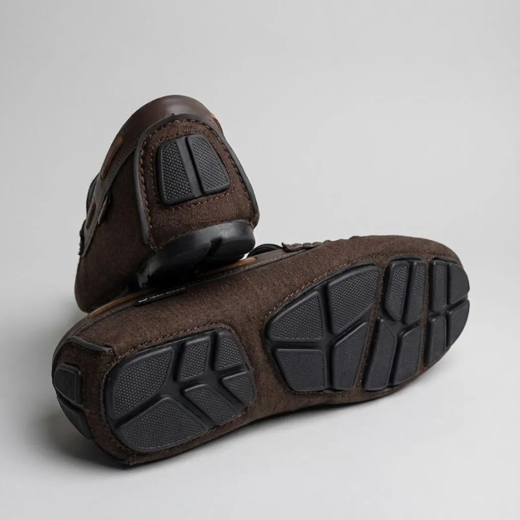 Par do modelo Mocassim Driver Riviera em Lona, na cor marrom, com um dos solados voltado para a câmera.