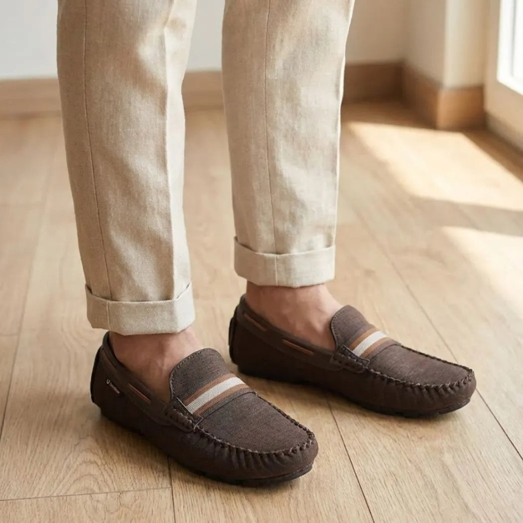 Mocassim Driver Riviera em Lona na cor marrom, usado com calça clara de barra dobrada.