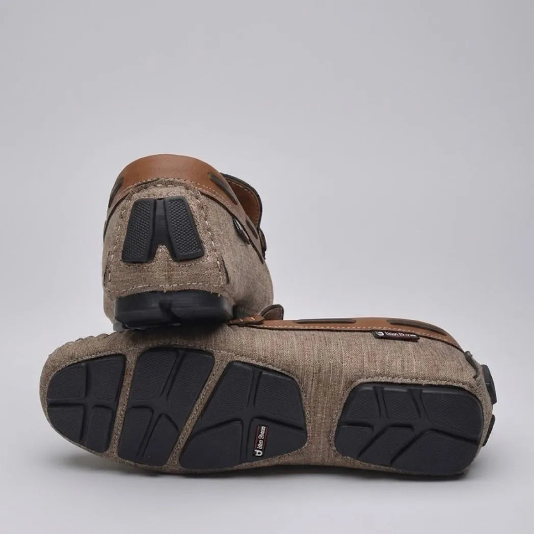 Par do modelo Mocassim Driver Riviera em Lona, na cor bege, com um dos solados voltado para a câmera.
