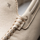 Mocassim Driver Vancouver de Couro Branco: detalhe do couro claro, emblema plano e costura do cabedal, sem ferragem metálica.