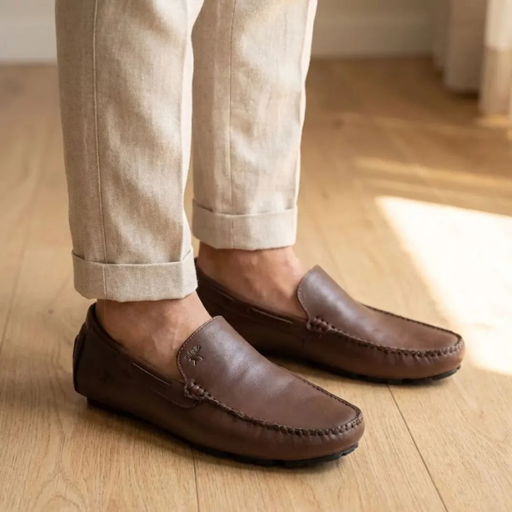 Mocassim Driver Vancouver de Couro na cor marrom-escuro, usado com calça clara de barra dobrada.