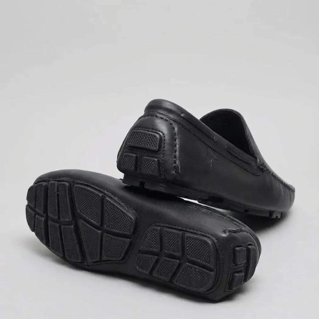 Par do modelo Mocassim Driver Vancouver de Couro, na cor preto, com um dos solados voltado para a câmera.
