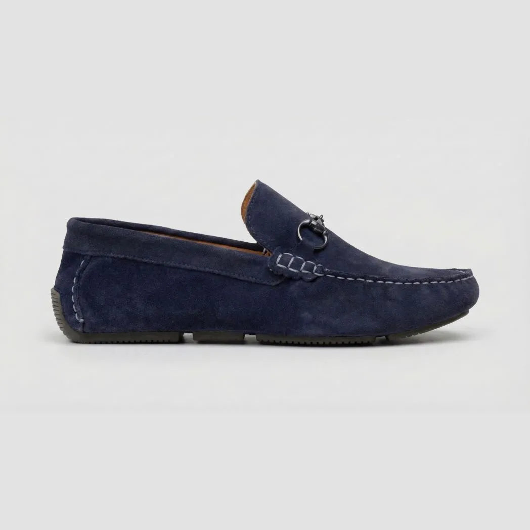 Mocassim Driver de Camurça Capri Dune: modelo azul-escuro de perfil, com pequena ferragem frontal e pinos na parte traseira.